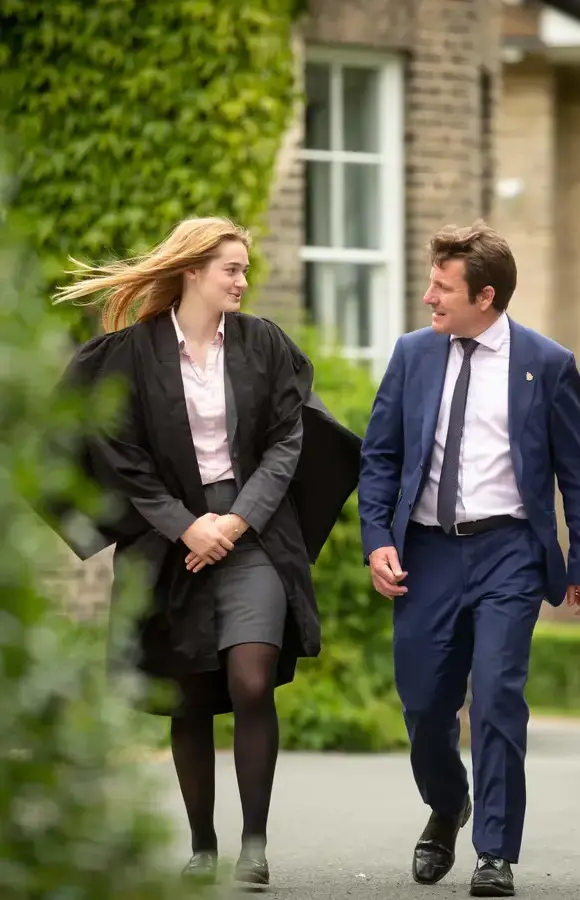 Pocklington School teacher talking to Sixth Form prefect in gown outside School  