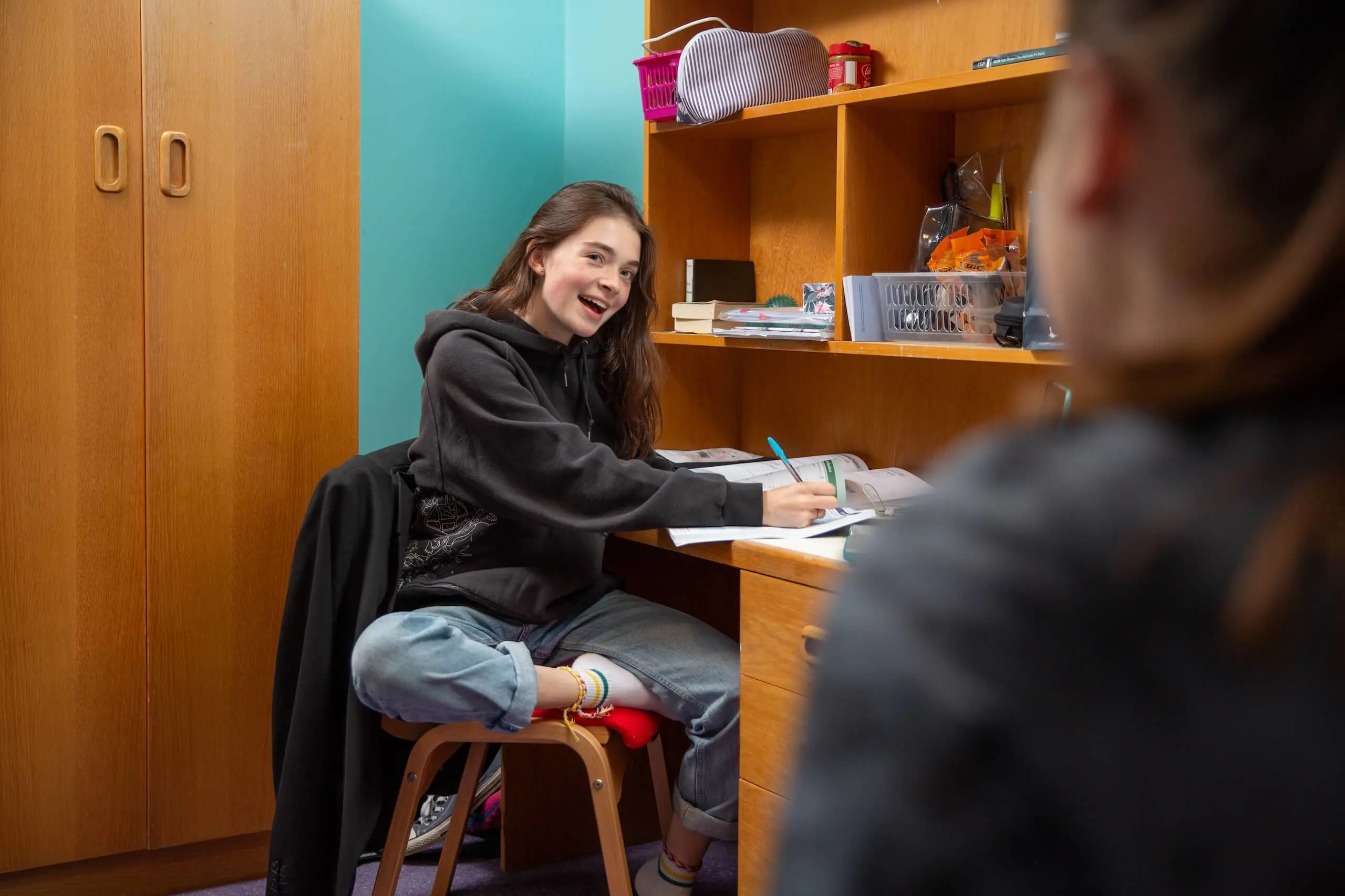 Pocklington School boarder at desk in boarding house, writing and smiling